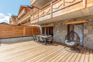 a patio with a table and chairs on a wooden deck at Les Terrasses de la Vanoise in Champagny-en-Vanoise