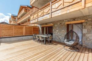 eine Terrasse mit einem Tisch und Stühlen auf einer Holzterrasse in der Unterkunft Les Terrasses de la Vanoise in Champagny-en-Vanoise