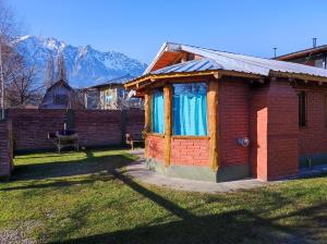 a small red brick house with blue curtains in a yard at Cabañas Los Lúpulos in El Bolsón