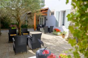 a patio with chairs and tables and a building at Hôtel Le Peu Breton in Sainte-Marie-de-Ré