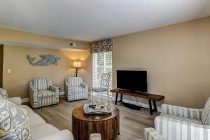 uma sala de estar com um sofá e uma televisão de ecrã plano em Harbour Master 103 em Hilton Head Island