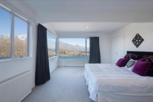 a bedroom with a large bed with purple pillows at Star Lane by Amazing Accom in Queenstown