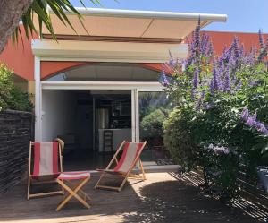 two chairs sitting on a deck in front of a house at LE CAP - bungalow vue mer et colline - Hauteur de Cassis in Cassis