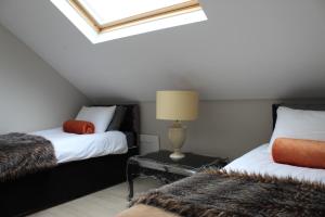 sypialnia na poddaszu z 2 łóżkami i lampką na stole w obiekcie Toadhall Rooms w mieście Muchalls