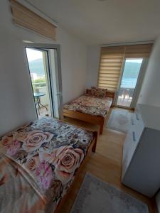 a bedroom with two beds and a window with roses at MANONI APARTMANI in Kumbor