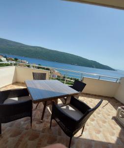 a table and chairs on a balcony with a view of the water at MANONI APARTMANI in Kumbor