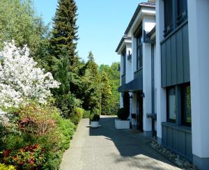 een loopbrug naast een gebouw met bloeiende bomen bij Appartementhaus Dr Domberg Wohnung 2 in Bad Zwischenahn