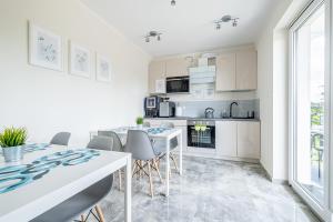 a kitchen and dining room with white cabinets and a table and chairs at Jakubowa Polana - pokoje in Łeba