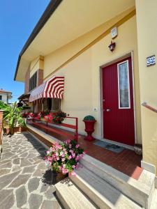 a building with a red door and flowers on the porch at villino Morena in Torre del Lago Puccini