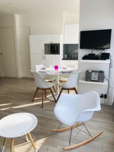 a dining room with white chairs and a table at Carré d’Or super 2 pièces in Nice