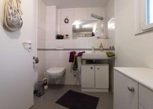 a white bathroom with a sink and a toilet at Häuschen am Silbersee in Kittlitz