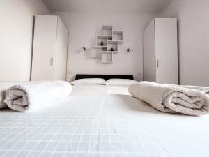 - une chambre blanche avec 2 lits et des serviettes sur le lit dans l'établissement RIAD Apartments, à Zgornje Škofije