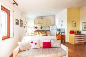 een woonkamer met een witte bank en een keuken bij Casa Sui Tetti in Baunei