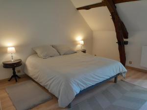 1 dormitorio con 1 cama blanca grande y 2 lámparas en Ravissante longère avec grand jardin et cheminée, en Pellevoisin