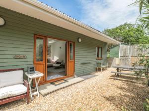 una casa verde con un banco y una mesa en The Stables, en Winscombe