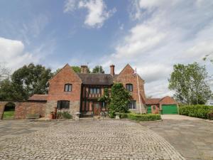 a large brick house with a cobblestone driveway at Rowlands House in Coalville