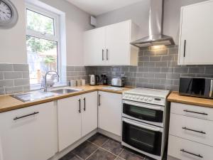a kitchen with white cabinets and a sink and a stove at 13 The Crescent in Llandrillo-yn-Rhôs