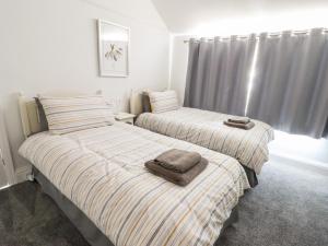 two beds in a bedroom with towels on them at 13 The Crescent in Llandrillo-yn-Rhôs