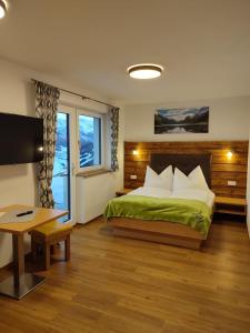 Schlafzimmer mit einem Bett, einem Schreibtisch und einem TV in der Unterkunft Appartement Kuschelzeit Jansenbichl in Wagrain