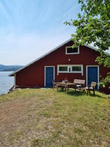 a red barn with a picnic table next to the water at Boathouse in Mjällom