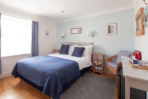 a bedroom with a blue and white bed and a window at The Artist Loft, Ensuite Guest Rooms, Porthleven in Porthleven