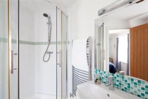 a bathroom with a shower and a sink and a mirror at The Artist Loft, Ensuite Guest Rooms, Porthleven in Porthleven