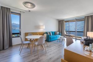 een woonkamer met een blauwe bank en een tafel en stoelen bij Parkhotel Brenscino Brissago in Brissago