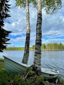 um barco sentado ao lado de duas árvores num lago em Costa Villa em Tahkovuori