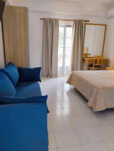 萊夫基米的住宿－Alykes Family Resort，一间卧室配有一张床和一张蓝色的沙发