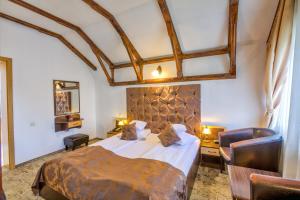 a bedroom with a large bed and two chairs at Pensiunea Ambient in Braşov