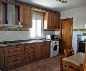 cocina con armarios de madera, lavadora y secadora en Chalet con piscina en Níjar, en Níjar