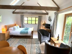 a bedroom with a bed and a chair in a room at A Delightful Barn in a Peaceful and Private Setting, Close to Dartmoor and the Beautiful Tamar Valley in Gunnislake