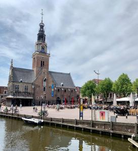 a large building with a clock tower next to a river at City room in Alkmaar