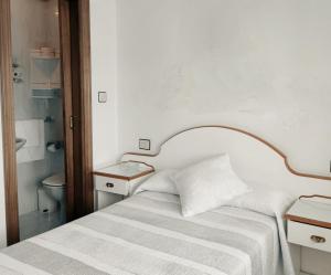 Habitación blanca con cama y baño. en Hostal J.B en Malpica