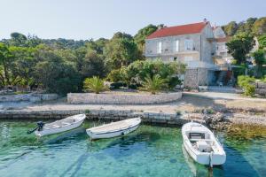 Drei Boote sind im Wasser in der Nähe eines Hauses angedockt. in der Unterkunft Guesthouse Sanela in Pomena