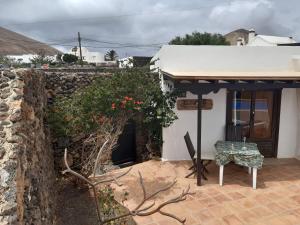 une maison blanche avec un mur en pierre et une chaise dans l'établissement Islabella Lanzarote habitaciones en Villa con entrada particular, à Tías