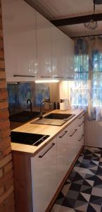 a kitchen with white cabinets and a black and white tile floor at Domek Anna Zawóz in Zawóz