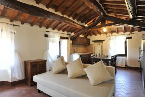 a living room with a white couch and a kitchen at La Casa Colonica in Tuoro sul Trasimeno