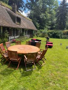 a wooden table and chairs in a yard at Chaleureuse chaumière proche Château et plages in Pleine-sève