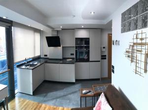 a large kitchen with white cabinets and a television at Apartamento Rosario 2 in Vigo