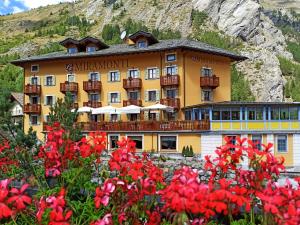 un hôtel dans les montagnes avec des fleurs au premier plan dans l'établissement Le Miramonti Hotel Restaurant & Wellness, à La Thuile