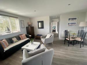 Una sala de estar con un sofá y sillas y una mesa. en 2 Bedroom cottage sleeps 4 with Hot-tub, & shared Pool use, en Sennen