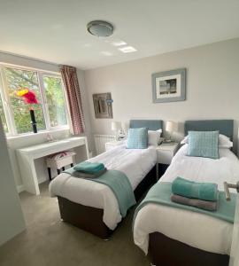 Un dormitorio con dos camas y una ventana. en 2 Bedroom cottage sleeps 4 with Hot-tub, & shared Pool use, en Sennen