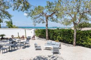 um pátio com cadeiras e mesas e a praia em B&B Villa Massimo em Porto Cesareo