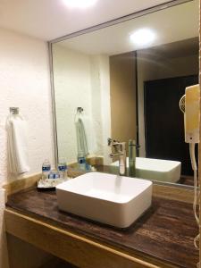 y baño con lavabo blanco y espejo. en Hotel Los Cocos Chetumal en Chetumal