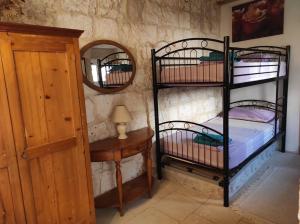 a room with two bunk beds and a table with a mirror at Traditional Maltese House in centre of Town in Mosta