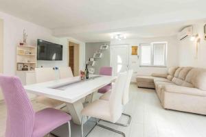 a living room with a white table and purple chairs at Agape Apartments in Biograd na Moru