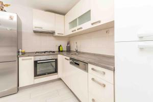 a kitchen with white cabinets and a stainless steel refrigerator at Agape Apartments in Biograd na Moru