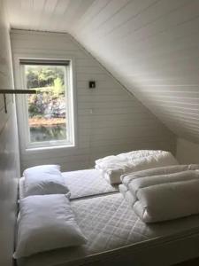 a bed with pillows in a room with a window at Flekkerøy sjøboder 4 soverom 8 senger in Kjere