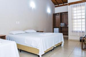 um quarto com uma cama grande e um cobertor branco em Hotel Fazenda Haras em Olímpia